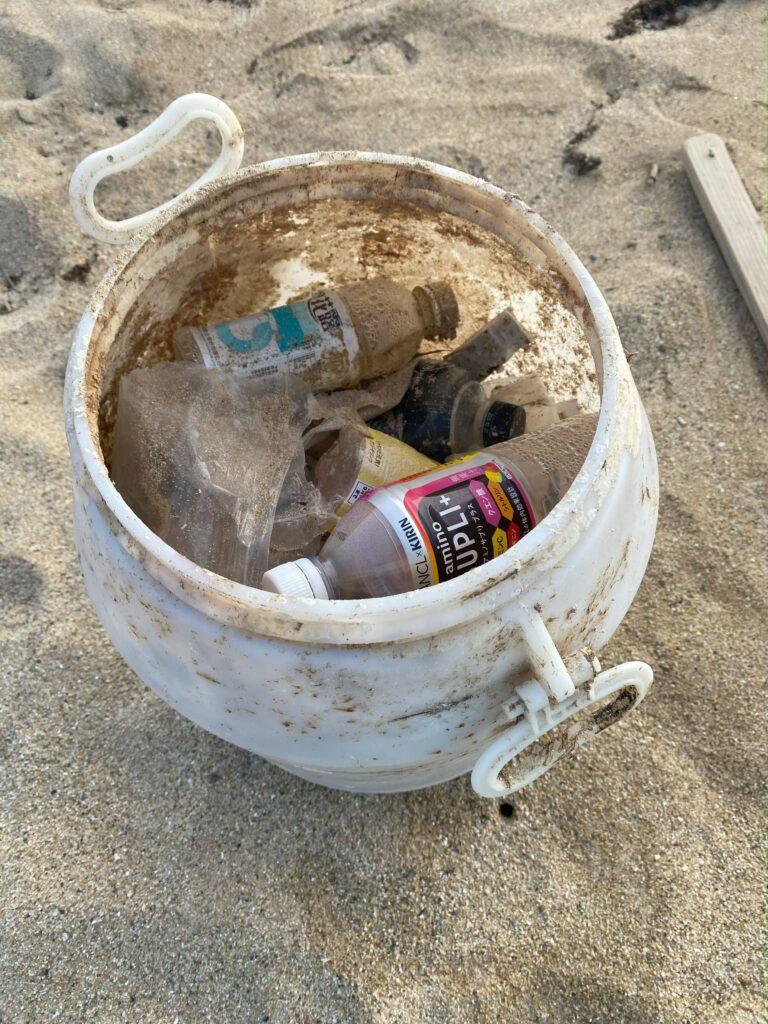 打ち上げられたプラスチック容器内に、ごみが入れられている様子