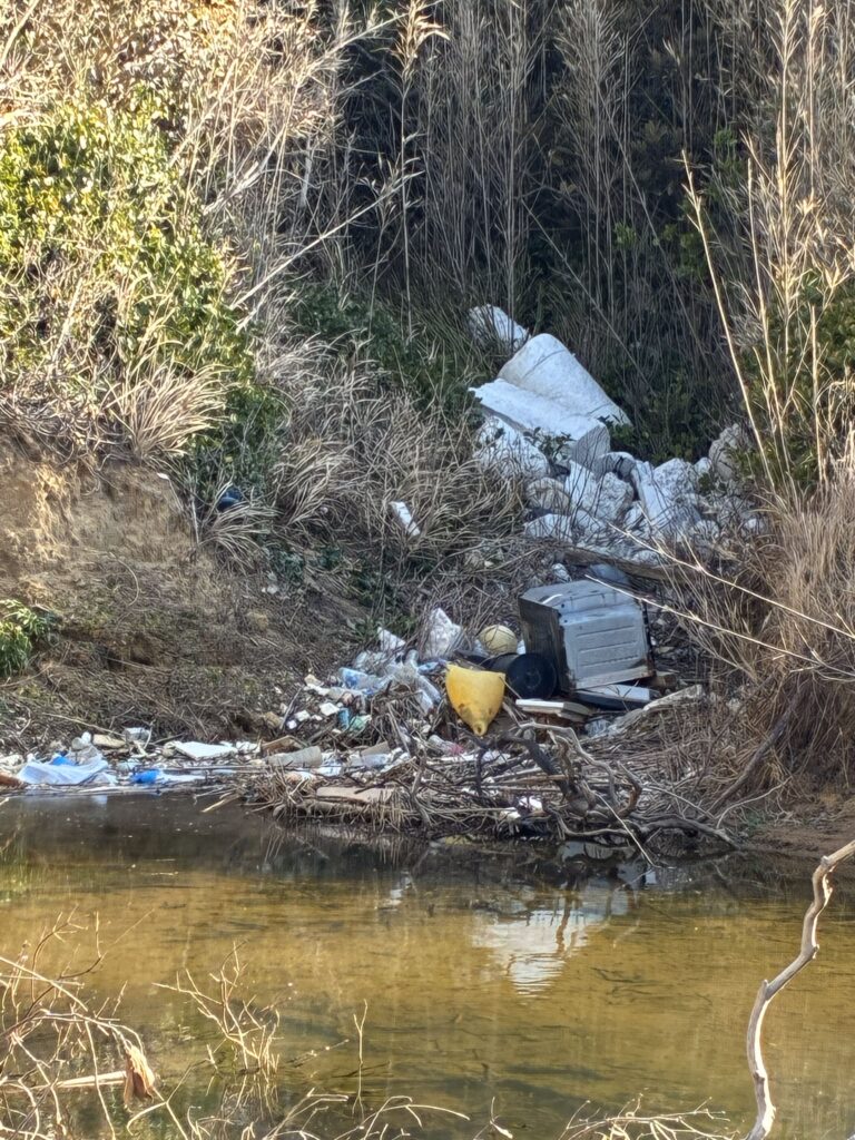 ２０２６年１月１８日　脇田海岸で抉れた砂浜に海水が滞留し、最奥には海洋ごみが堆積している様子